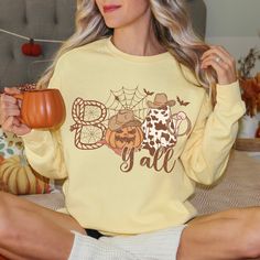 Boo Y'all cute Halloween Shirt. Witty and warm, you'll love this Western Halloween inspired crewneck!  Luxurious comfort and style are what this unisex, garment-dyed sweatshirt is all about. It's made with 80% ring-spun cotton and 20% polyester and the fabric is 3-end garment-dyed, ring-spun, color-blast fleece with a 100% cotton face. Each sweatshirt comes with a relaxed fit, a rolled-forward shoulder, and a back neck patch.  .: 80% ring-spun cotton, 20% polyester .: Medium-heavy fabric (9.5 oz Cute Yellow Sweatshirt For Fall, Fun Long Sleeve Fall T-shirt, Fun Fall Top With Letter Print, Fun Letter Print Top For Fall, Fun Yellow Tops For Fall, Fun Letter Print Tops For Fall, Fun Yellow Fall Tops, Yellow Letter Print Sweatshirt For Fall, Halloween Crewneck Sweatshirt