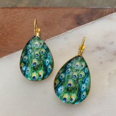 Turquoise And Green Peacock Feather Print. Glass Or Gun Metal Dome. Gold Base. 18x25mm Stone. 2” Drop. Bundle Discounts. Many Styles And Colors To Choose From. 500+ Green Peacock Design Drop Earrings, 90s Earrings, Peacock Feather Print, Green Peacock, Vintage Drop Earrings, Spider Earrings, Crystal Fashion, Bronze Earrings, Ear Cuff Earings