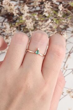 a woman's hand wearing a gold ring with an emerald stone in the middle