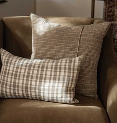 two pillows sitting on top of a brown couch