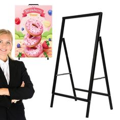 a woman standing in front of a sign with a doughnut on it and a poster behind her