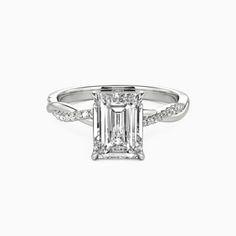 Showcasing an exquisite emerald-cut center stone, this side-stone engagement ring radiates elegance and sophistication. A shimmering strand of gems is delicately entwined with a lustrous metal ribbon, creating a beautiful harmony that adds a distinctive touch to the design. This ring, a blend of classic and modern aesthetics, perfectly symbolizes the unique love story it represents. *Each piece is handmade, resulting in a potential variance of 0.1-0.2mm during measurement. Please refer to the ac White Emerald Cut Emerald Ring, Wedding Diamond Ring With Side Stones In Emerald Cut, Wedding Diamond Ring Emerald Cut With Side Stones, Gia Certified Elegant Square Cut Diamond Ring, Emerald Cut Diamond Wedding Ring With Side Stones, Wedding Emerald Cut Diamond Ring With Side Stones, Elegant Gia Certified Square Cut Diamond Ring, Elegant Radiant Cut Emerald Promise Ring, Elegant Square Cut Emerald Ring With Center Stone