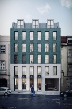 a person standing in front of a tall building with many windows on the top floor