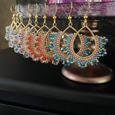 several pairs of earrings hanging from a hook on a table next to a purple vase