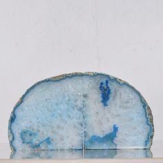 a blue and white object sitting on top of a glass shelf next to a wall