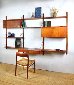 a wooden desk and chair in front of a wall mounted book shelf with books on it