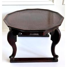 an old wooden table sitting on top of a white floor next to a door and window