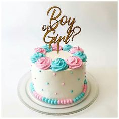 a white cake with blue and pink frosting on top that says boy or girl