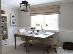 a room with a table, chair and lamp in it next to a book shelf