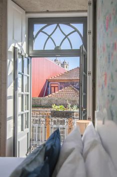 an open window with a view of the roof tops and buildings in the back ground