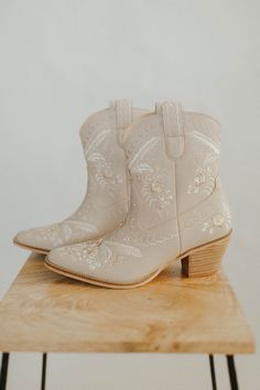 a pair of white cowboy boots sitting on top of a wooden table