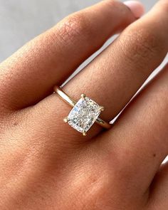 a woman's hand with a diamond ring on top of her finger and an engagement band