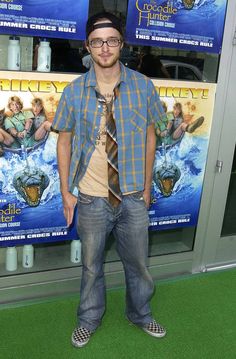 a man standing on the green carpet in front of a movie poster at an event