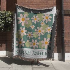 a woman standing next to a large green and white blanket with pink flowers on it