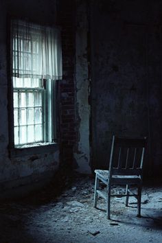 an empty chair sitting in front of a window