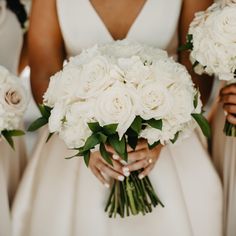 the bridesmaids are holding bouquets of white roses