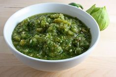 a white bowl filled with green food on top of a wooden table