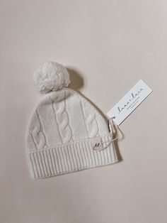 Introducing our delightful cable knit baby beanie, the perfect accessory to keep your little one cozy and stylish. Crafted with utmost care, this beanie is made from 100% Merino wool, ensuring exceptional warmth and comfort for your precious bundle of joy. Designed with a classic cable knit pattern, this beanie showcases a timeless style that complements any outfit. The intricate detailing adds a touch of sophistication to your baby's ensemble, making them the center of attention wherever they g Cute White Knitted Beanie, Cozy White Hat, Cute Cream Soft Knit Hat, Cozy Warm White Bonnet, Cozy Warm White Hat, Adjustable Warm White Bonnet, White Fitted Warm Beanie, Cute White Soft Knit Beanie, White Warm Beanie Bonnet