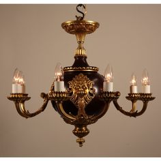 a chandelier with five candles on it and a lion head in the center