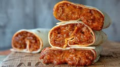 three burritos stacked on top of each other with meat in the wrapper