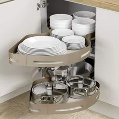 an open cabinet with plates and pans in the bottom drawer, next to a counter