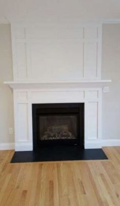 an empty living room with a fireplace and hard wood floors