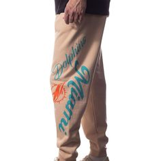 These The Wild Collective Graphic Joggers are the perfect way to blend your Miami Dolphins-inspired sportswear with streetwear style. Featuring team graphics down both legs for a bold aesthetic that allows for uninhibited expression of ones Miami Dolphins fandom, these pants are unlike anything in your selection of game day gear.These The Wild Collective Graphic Joggers are the perfect way to blend your Miami Dolphins-inspired sportswear with streetwear style. Featuring team graphics down both legs for a bold aesthetic that allows for uninhibited expression of ones Miami Dolphins fandom, these pants are unlike anything in your selection of game day gear.Machine wash, tumble dry lowScreen print graphicsTwo side pocketsImportedElastic waistbandMaterial: 73% Cotton/27% PolyesterOfficially lic Baggy Letter Print Bottoms For Leisure, Hip Hop Joggers With Letter Print For Leisure, Casual Sports Joggers With Logo Print, Hip-hop Style Leisure Joggers With Letter Print, Casual Pants For Sports Season Events, Hip Hop Bottoms With Letter Print In Relaxed Fit, Cotton Sports Bottoms With Graphic Print, Hip Hop Style Joggers With Letter Print, Hip Hop Relaxed Fit Joggers With Letter Print