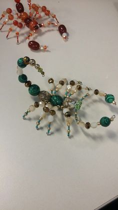 several beaded necklaces are laying on a white surface, including one with green and brown beads