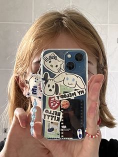 a woman holding up her cell phone in front of her face with stickers on it