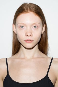 a woman with red hair and blue eyes is looking at the camera while wearing a black tank top