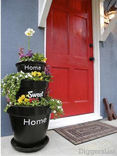 three flower pots are stacked on top of each other in front of a red door