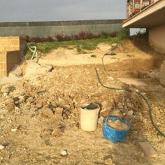 a blue bucket sitting on top of a pile of dirt next to a brick building