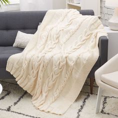 a couch with a blanket on it in a living room next to a table and chair