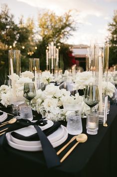 the table is set with white flowers and black napkins