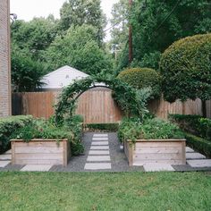 an outdoor garden with wooden planters and stone walkway