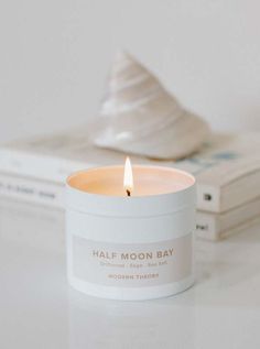 half moon bay candle sitting on top of a table next to books and a stack of magazines