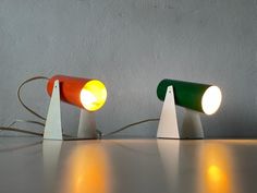 three different colored lamps sitting next to each other on top of a table in front of a wall