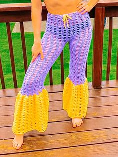 a woman is standing on a deck wearing purple and yellow knitted leggings