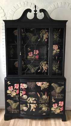 a black china cabinet with flowers painted on it