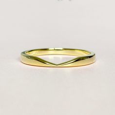 a yellow gold wedding band on a white surface with the word love written across it