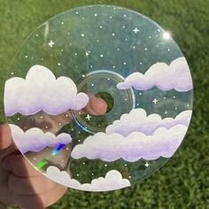 a person holding up a glass ball with clouds and stars on it in the grass