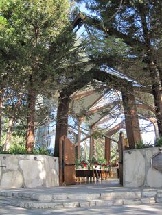 the entrance to an outdoor venue with trees and flowers on it's sides, surrounded by stone steps