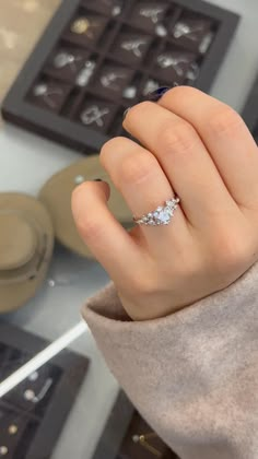 a woman's hand with a diamond ring on it, in front of some chocolates