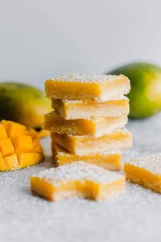 several pieces of cake sitting on top of a table next to mangoes and limes