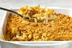 a casserole dish filled with macaroni and cheese topped with a spoon