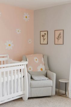 a baby's room with pink and white flowers on the wall