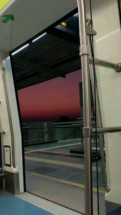 an open door on a subway train at dusk with the sun setting in the distance