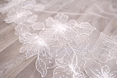 an image of flowers on the floor with white lace overlays and wood floors