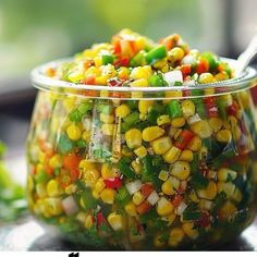 a glass bowl filled with corn and vegetables