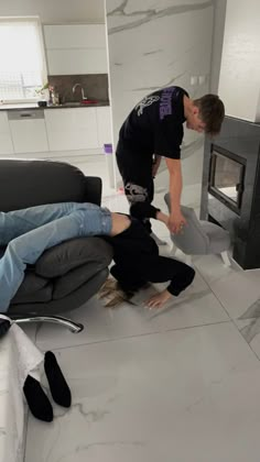 a man laying on the floor in front of a tv while another person stands next to him